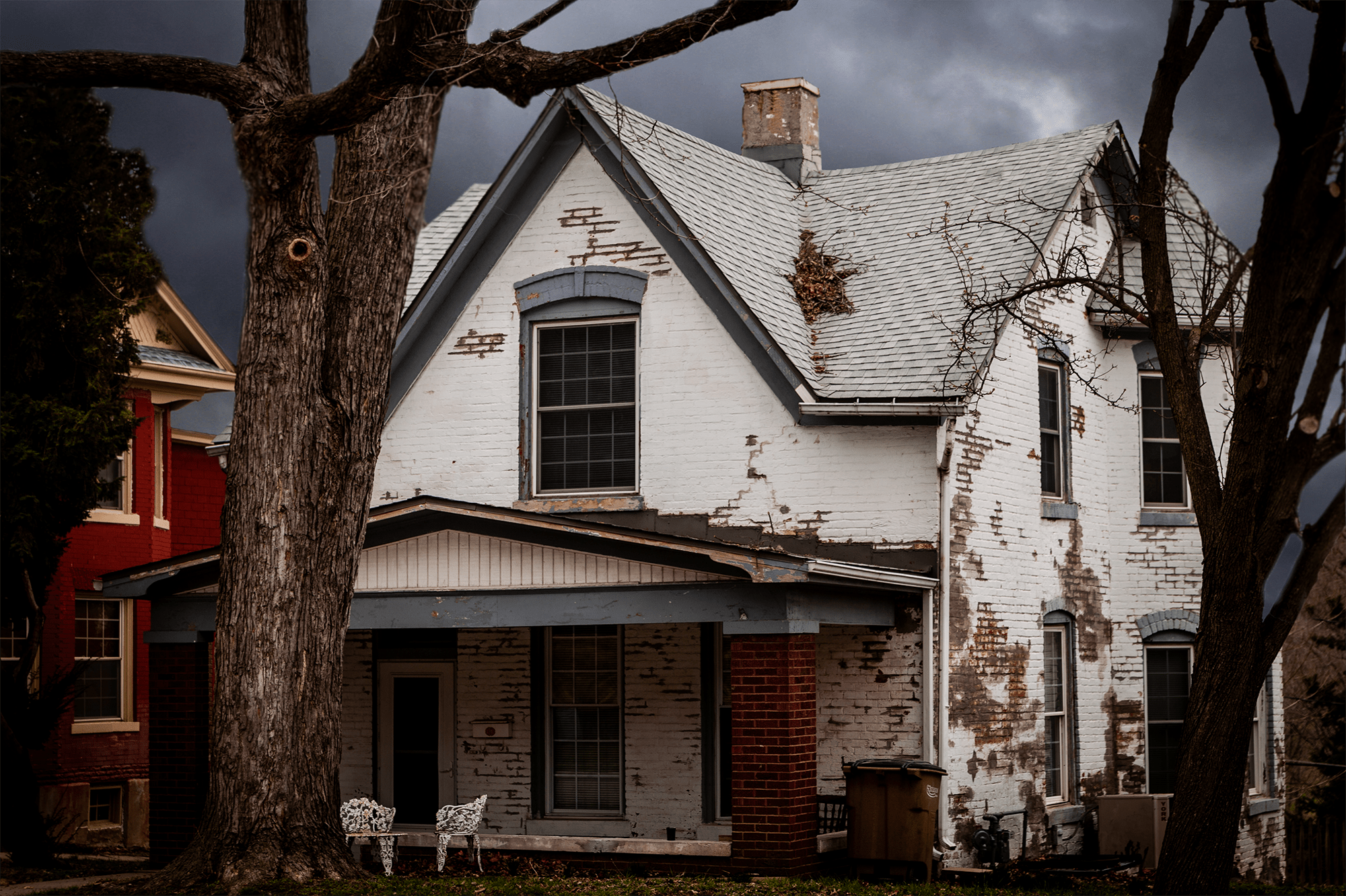 A spooky white brick house that looks old and crumbling